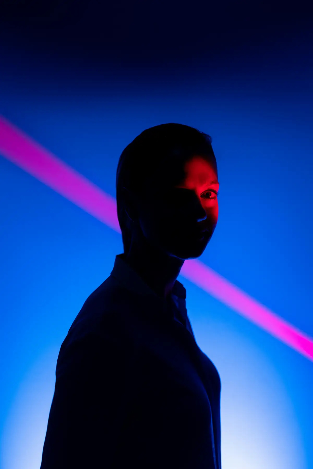 A face half in shadow, lit by a single line of red light